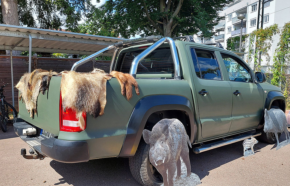 Jäger Max Vogel zu Besuch an der Schöpflin Schule mit seinem Info-Mobil »Lernort Natur«, Zu sehen ist ein grünes Auto auf dem Tierfelle liegen.