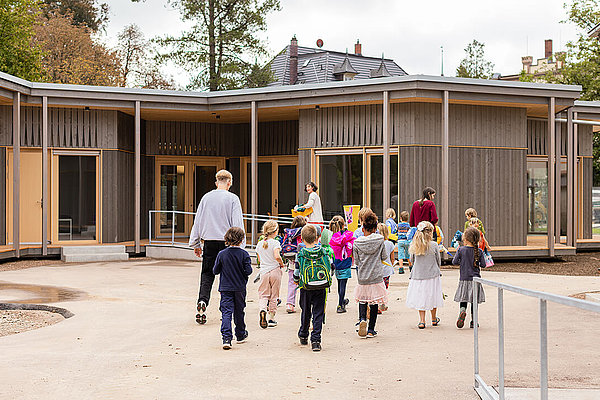 Kinder laufen über den Schulhof in ein Gebäude der Schöpflin Schule.