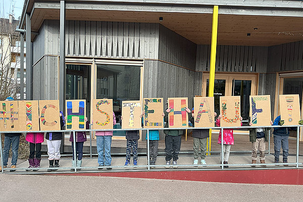 Bundesweite Aktion #IchStehAuf an der Schöpflin Schule, Kiunder halten kreativ gestaltete Schilder hoch