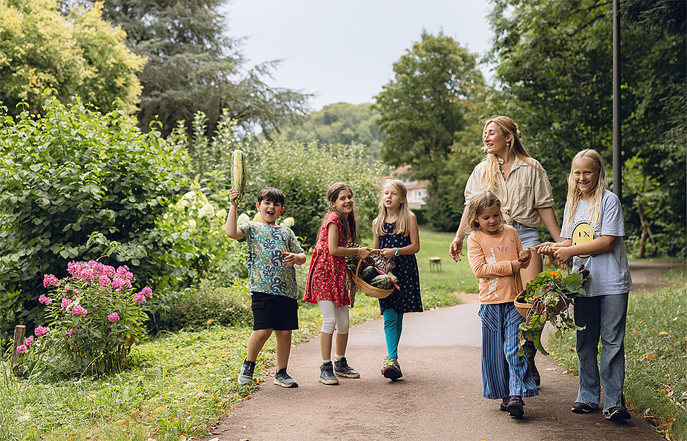 Die Schüler:innen mit Gärtnerin Sarah Bernhard im schuleigenen Bauerngarten